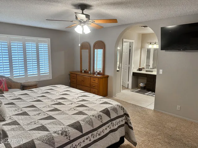 a bedroom with a large bed a flat tv screen and a chandelier