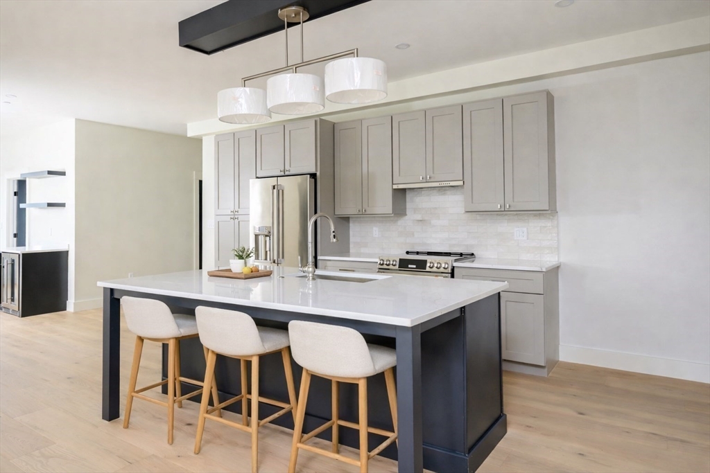 21 Tanglewood Road, Unit 3 Boston, MA 02126 - Photo 1 of 22 a kitchen with stainless steel appliances granite countertop a dining table chairs refrigerator and cabinets