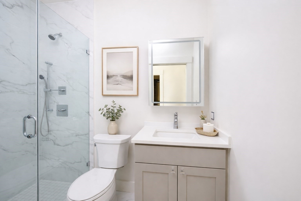 21 Tanglewood Road, Unit 3 Boston, MA 02126 - Photo 13 of 22 a bathroom with a toilet sink vanity and mirror