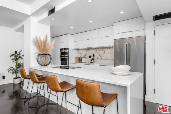 a kitchen with stainless steel appliances granite countertop a table chairs in it and wooden floors