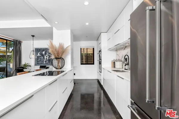 a large white kitchen with a sink and stainless steel appliances