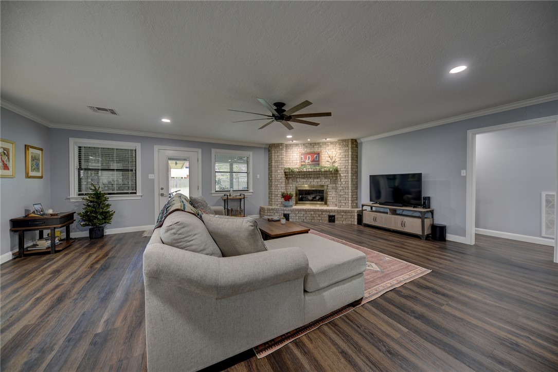 1600 Pecan Street Brenham, TX 77833 - Photo 8 of 33 Spacious living area with ceiling fan, crown molding, dark wood-style floors, a fireplace, and baseboards