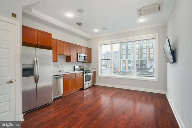 a large kitchen with stainless steel appliances granite countertop a refrigerator a sink dishwasher a stove and a large refrigerator with wooden floor