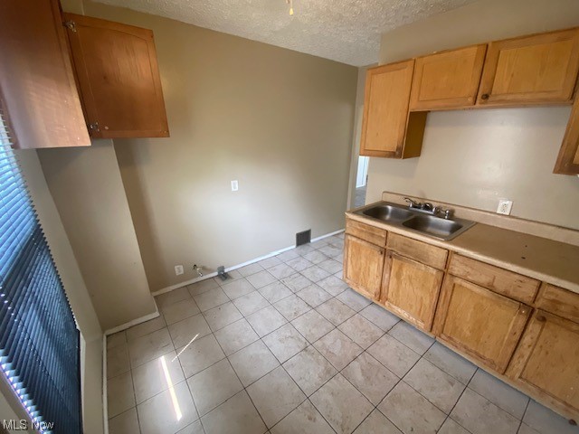 921 Rudyard Road Cleveland, OH 44110 - Photo 8 of 31 Kitchen with light tile flooring, brown cabinets, and a textured ceiling