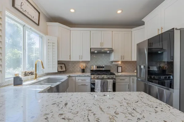 a kitchen with stainless steel appliances granite countertop a sink stove and cabinets