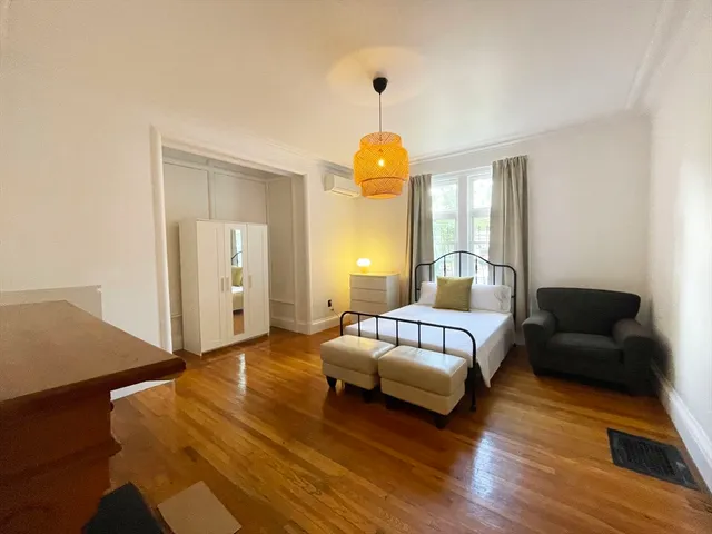 a spacious bedroom with a bed and wooden floor