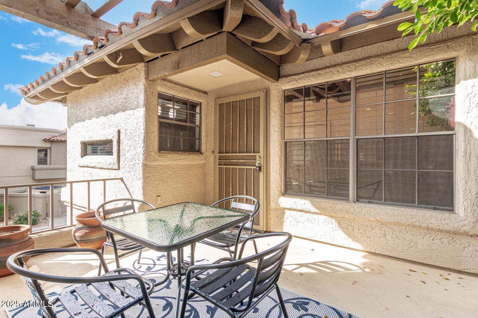 a patio with a table and chairs and potted plants
