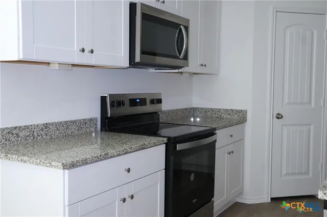 a kitchen with granite countertop a sink and a stove
