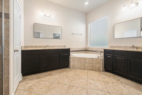 a spacious bathroom with a granite countertop sink a mirror and a bathtub
