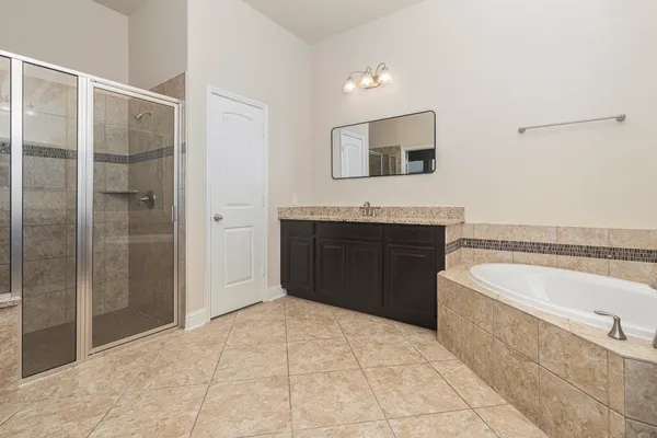 a spacious bathroom with a tub sink and mirror