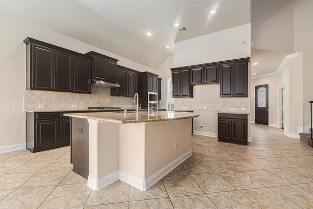 a kitchen with kitchen island granite countertop a stove top oven microwave and cabinets