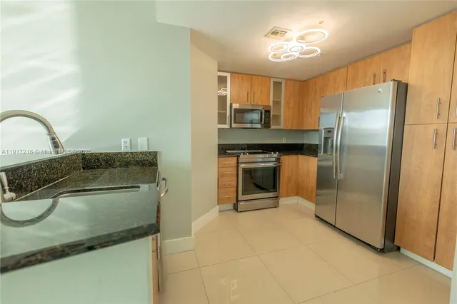 a kitchen with stainless steel appliances granite countertop a sink and a refrigerator