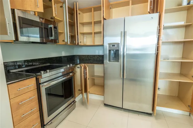 a view of a refrigerator in kitchen and an empty room