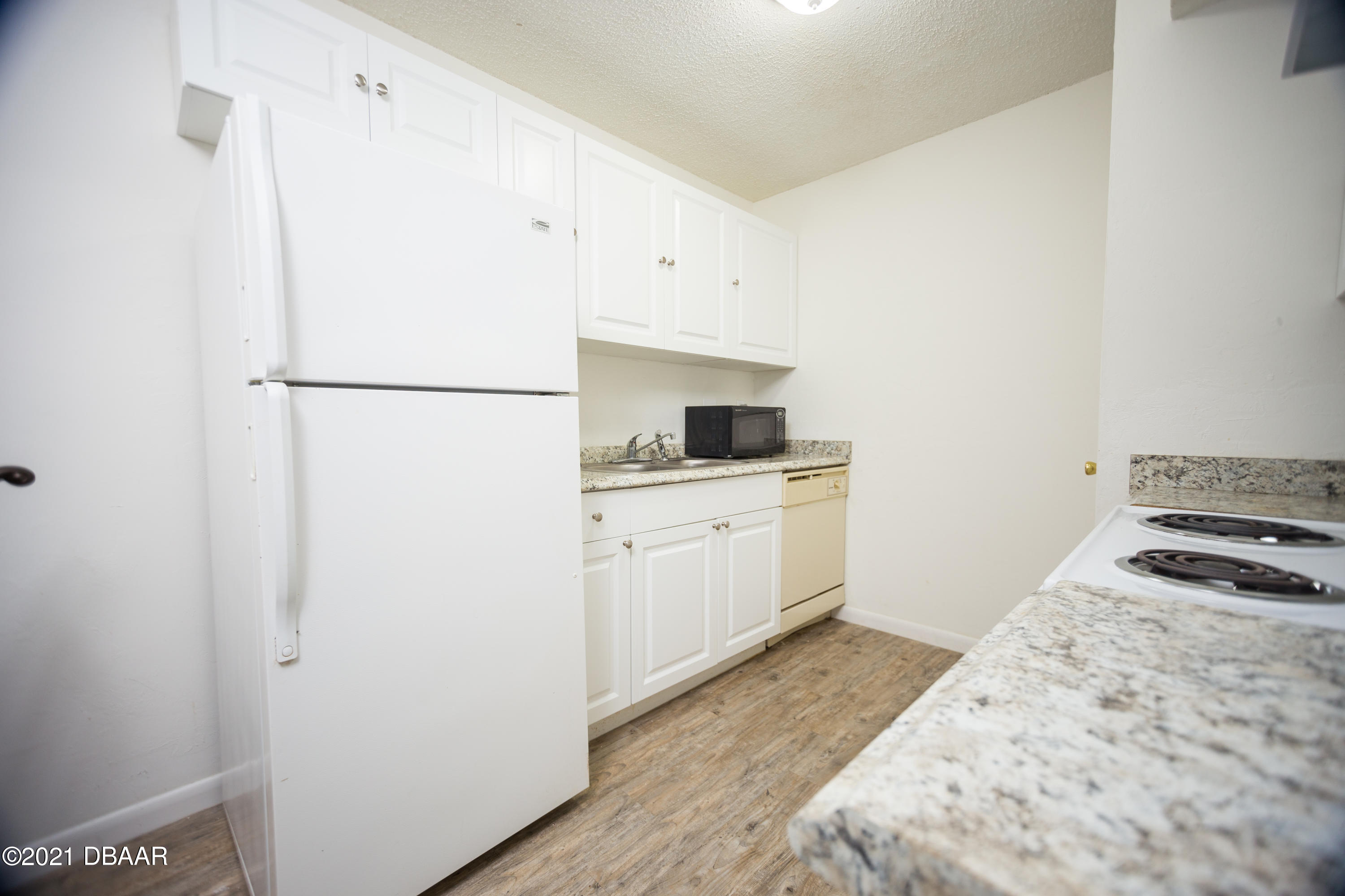 1600 Big Tree Road, Unit B8 South Daytona, FL 32119 - Photo 16 of 27 a kitchen with a white stove refrigerator and white cabinets with wooden floor