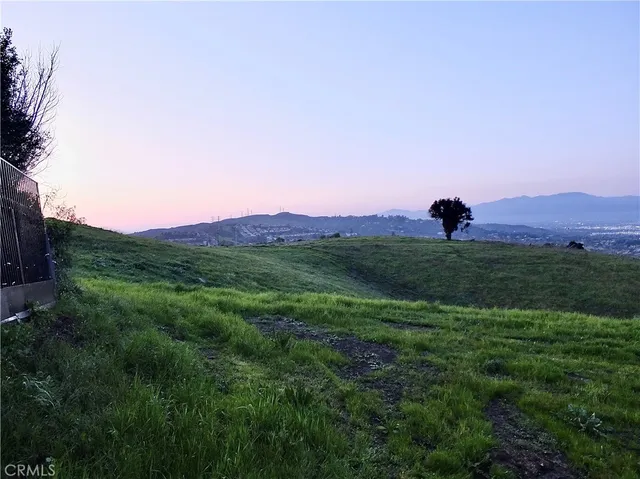 a view of a lush green outdoor space with a swimming pool and valleys in the background
