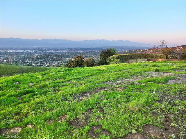 a view of a lush green outdoor space with a swimming pool and valleys in the background