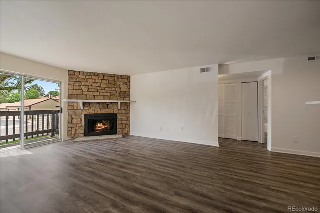 an empty room with wooden floor fireplace and windows
