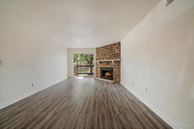 a view of empty room with fireplace and wooden floor