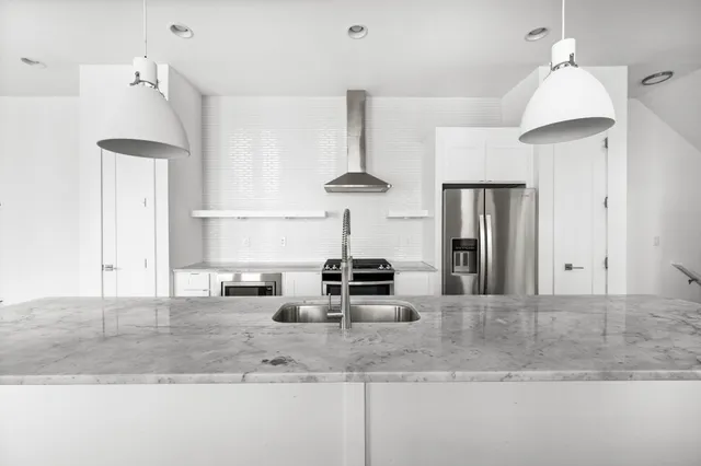 a kitchen with stainless steel appliances granite countertop a sink a refrigerator and a stove