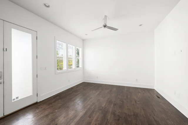 an empty room with wooden floor and windows