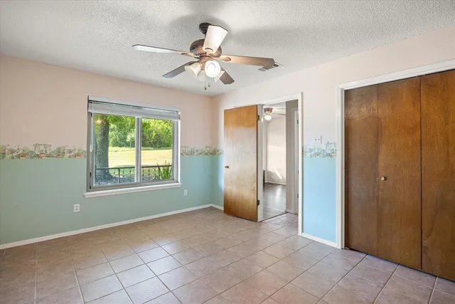 a view of an empty room with window and chandelier fan
