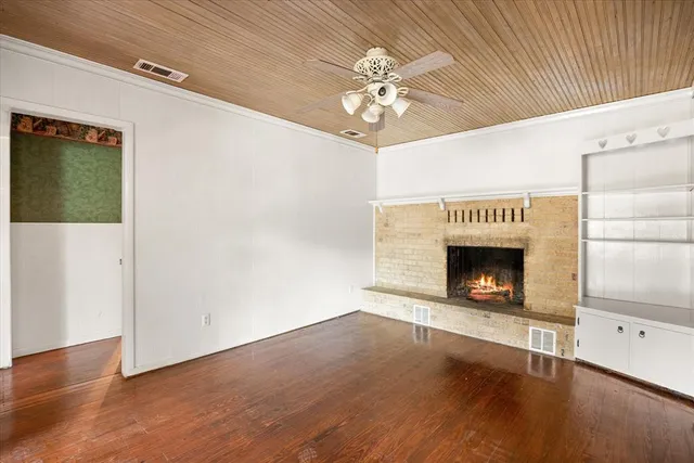 a view of an empty room with wooden floor and a fireplace