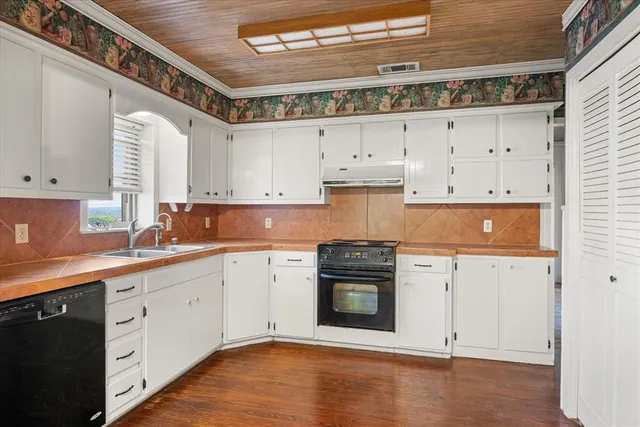 a kitchen with stainless steel appliances granite countertop a stove a sink and white cabinets