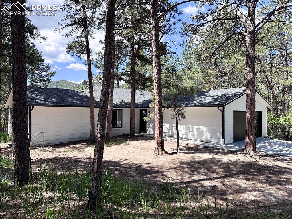 View of front of property featuring concrete driveway, a garage, and a shingled roof