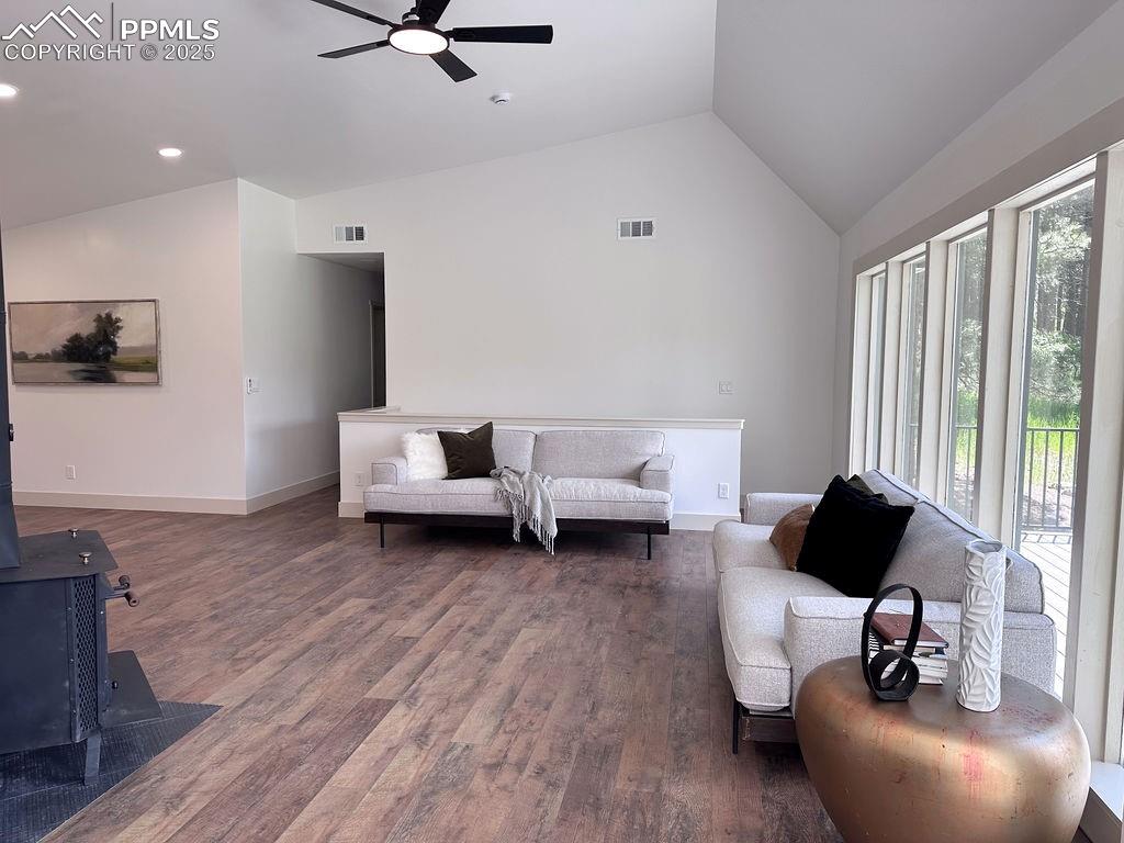 14546 Pine View Road Larkspur, CO 80118 - Photo 11 of 37 Living room featuring lofted ceiling, ceiling fan, wood finished floors, a wood stove, and recessed lighting