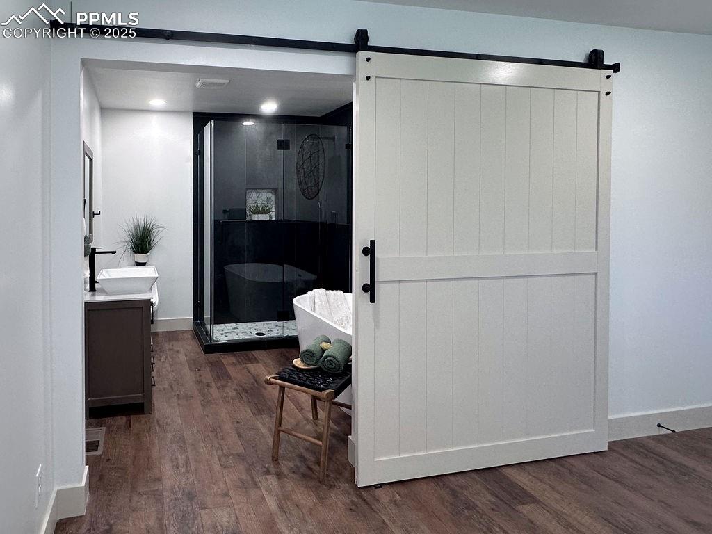 14546 Pine View Road Larkspur, CO 80118 - Photo 19 of 37 Full bath with vanity, wood finished floors, and a shower stall