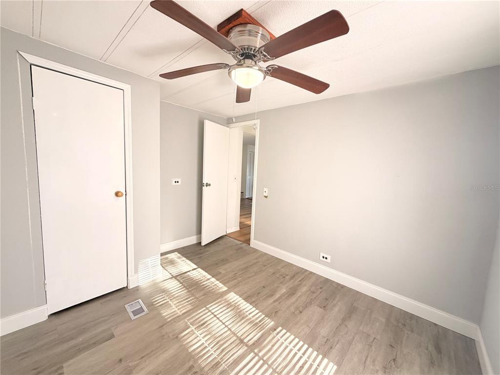 26352 Mc Allister Street Brooksville, FL 34602 - Photo 19 of 26 an empty room with wooden floor chandelier fan and closet