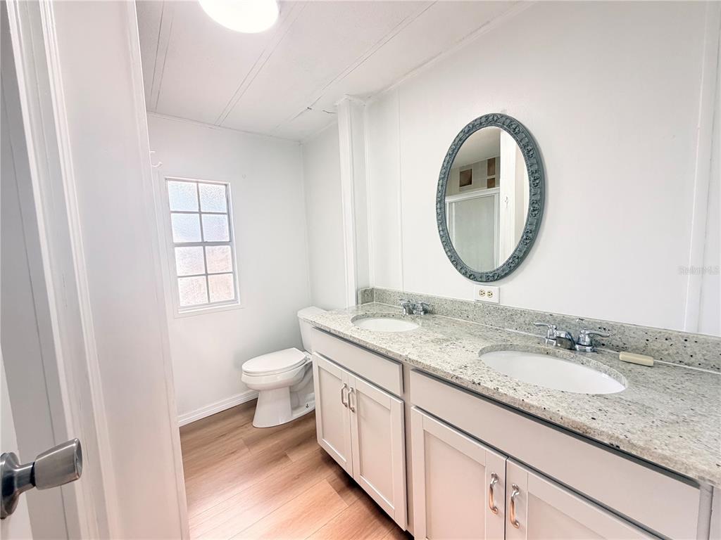 26352 Mc Allister Street Brooksville, FL 34602 - Photo 21 of 26 a bathroom with a granite countertop toilet a sink and a mirror