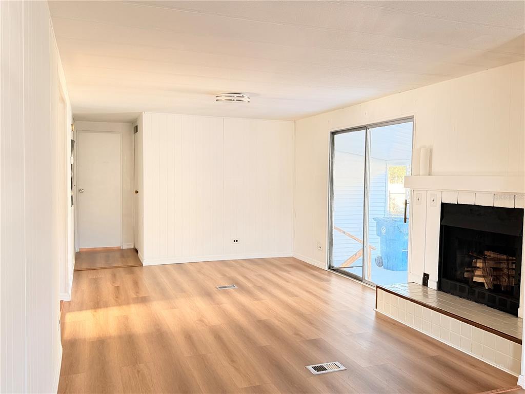 26352 Mc Allister Street Brooksville, FL 34602 - Photo 25 of 26 a view of an empty room with wooden floor fireplace and a window