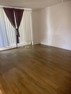 an empty room with wooden floor and window