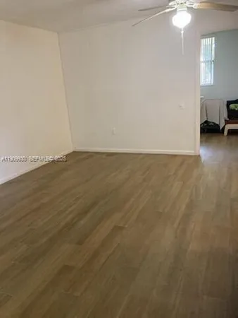 a view of an empty room with window and wooden floor