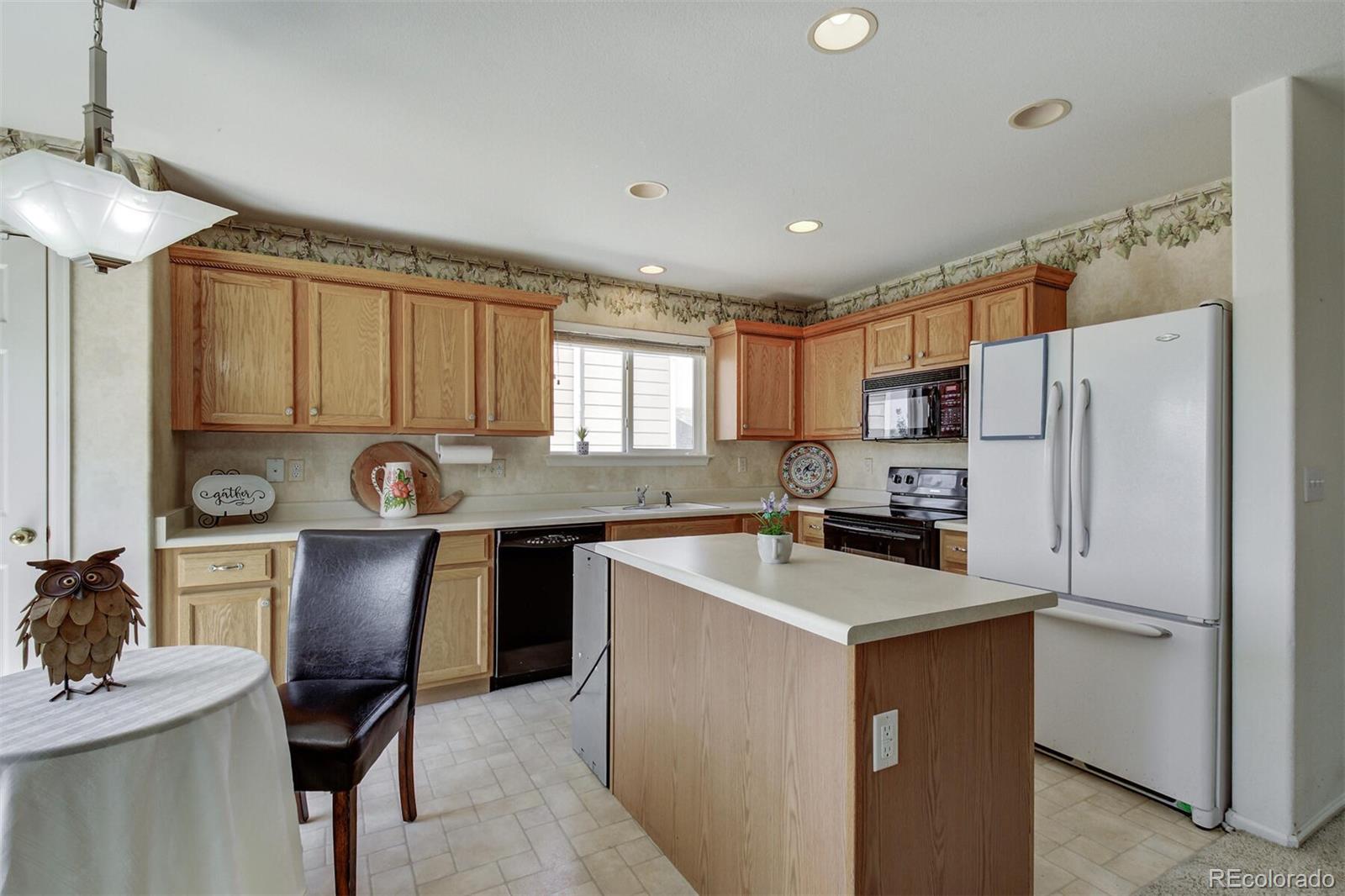 5555 South Rome Street Aurora, CO 80015 - Photo 11 of 34 a kitchen with a refrigerator a stove a sink cabinets and a window