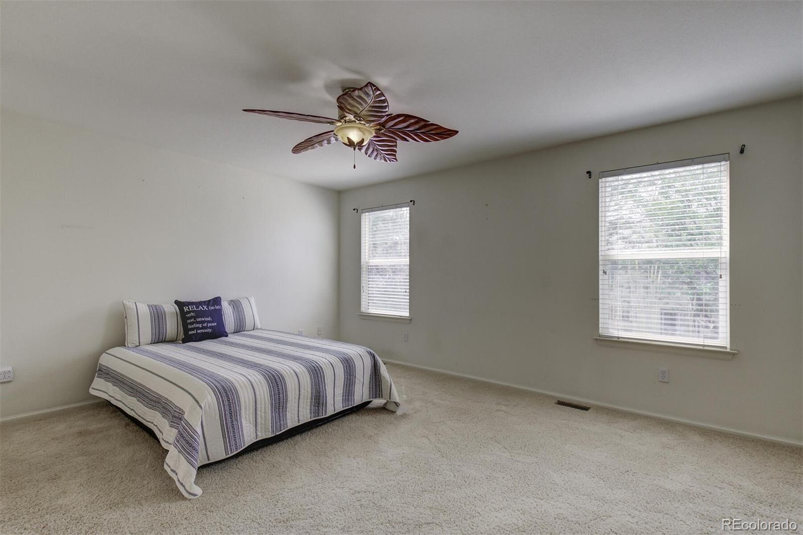 5555 South Rome Street Aurora, CO 80015 - Photo 18 of 34 a bedroom with a large bed and a chandelier
