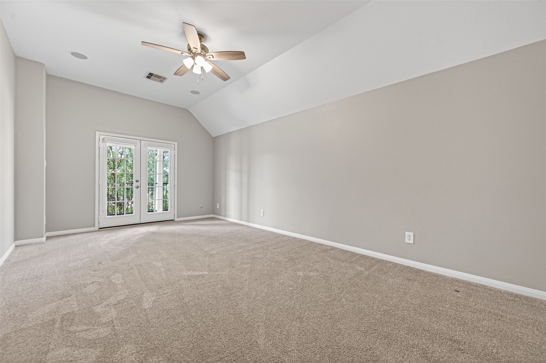 7003 Bristol Memorial Drive Spring, TX 77379 - Photo 29 of 40 Versatile flex room in this Spring TX 77379 home featuring vaulted ceilings, neutral finishes, and direct access to a private balcony overlooking the community lake. French doors provide natural light and seamless indoor-outdoor connection, making this space ideal as a sixth bedroom, media room, home office, or private retreat. Plush carpeting and elevated positioning enhance the quiet, upper-level setting. Located in this spacious 5+ bedroom home near The Woodlands, the balcony adds a rare outdoor extensio