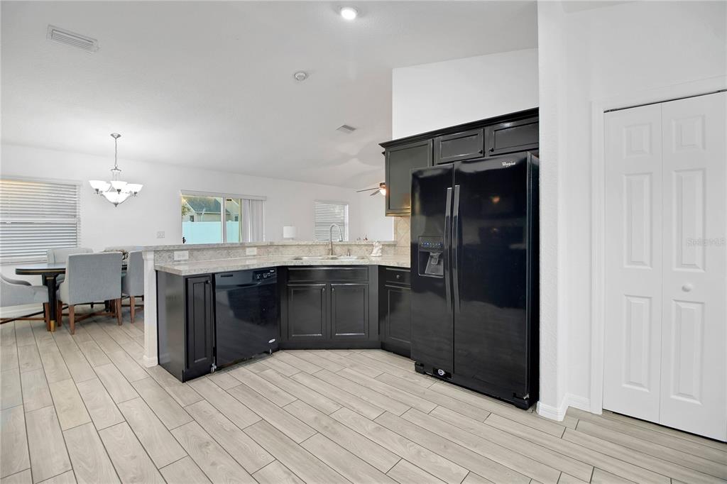 314 Stone Castle Loop Lady Lake, FL 32159 - Photo 12 of 42 a kitchen with stainless steel appliances kitchen island granite countertop a refrigerator and a sink