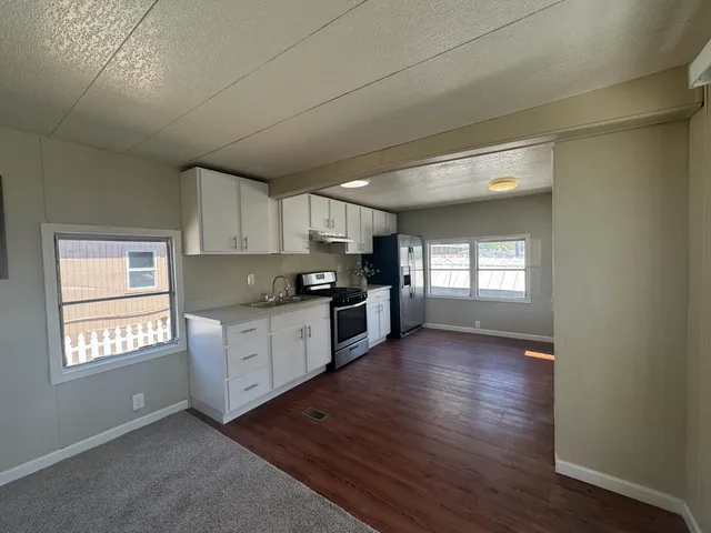 a kitchen with granite countertop a stove a sink and a refrigerator