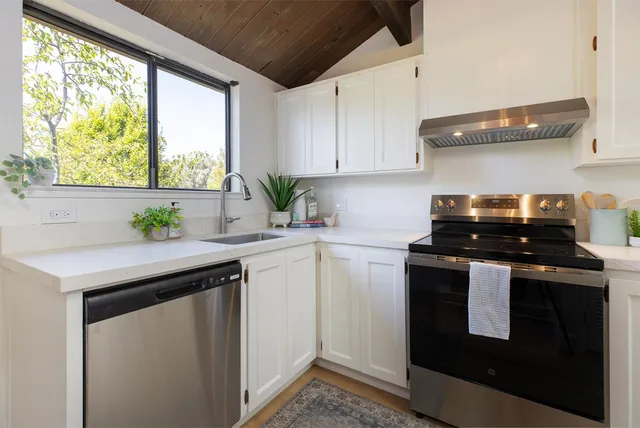a kitchen with stainless steel appliances granite countertop a sink a stove a microwave a sink and white cabinets