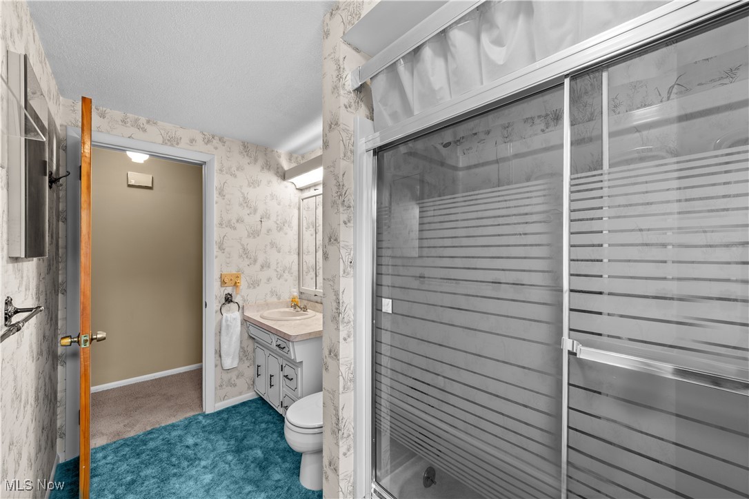 648 Rehwinkle Road Northfield, OH 44067 - Photo 24 of 38 Full bath with wallpapered walls, vanity, a shower stall, and a textured ceiling