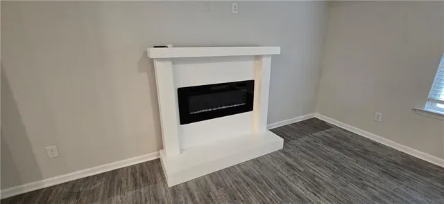 a view of an empty room with wooden floor fireplace and a window