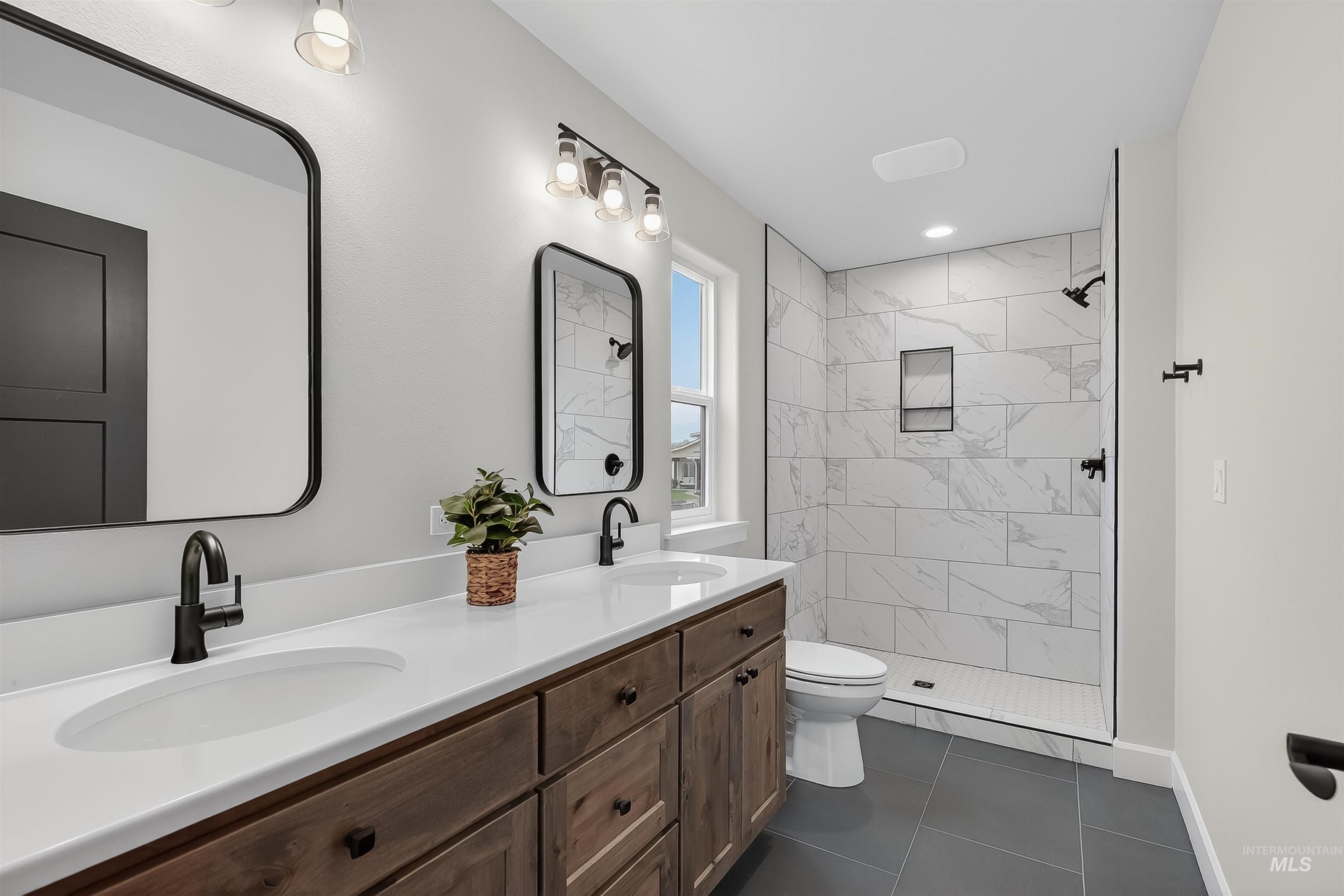 1725 Pathway Court Lewiston, ID 83501 - Photo 21 of 37 Bathroom featuring double vanity, a shower stall, and dark tile patterned flooring