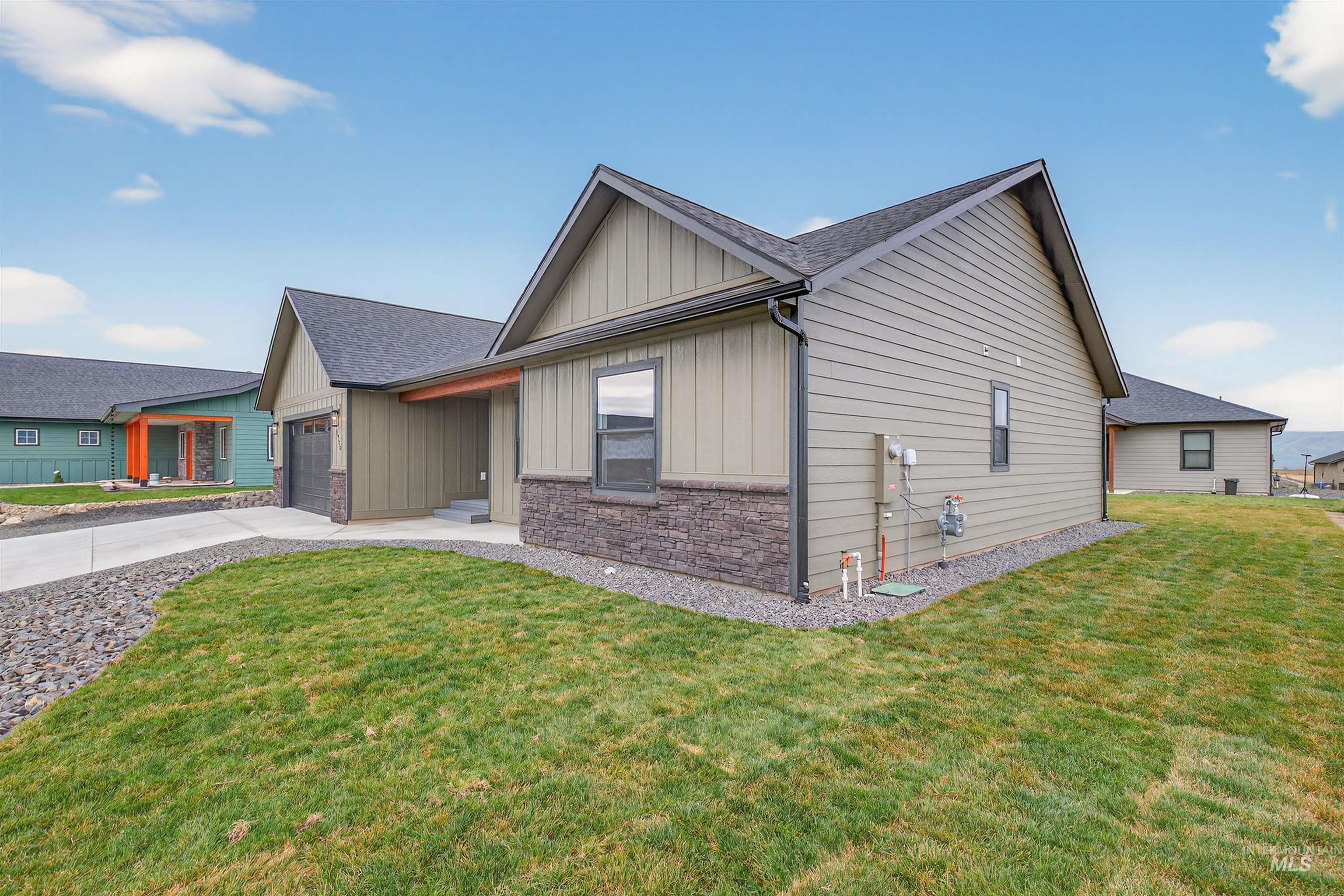 1725 Pathway Court Lewiston, ID 83501 - Photo 35 of 37 View of front of house featuring board and batten siding, a front yard, driveway, and stone siding