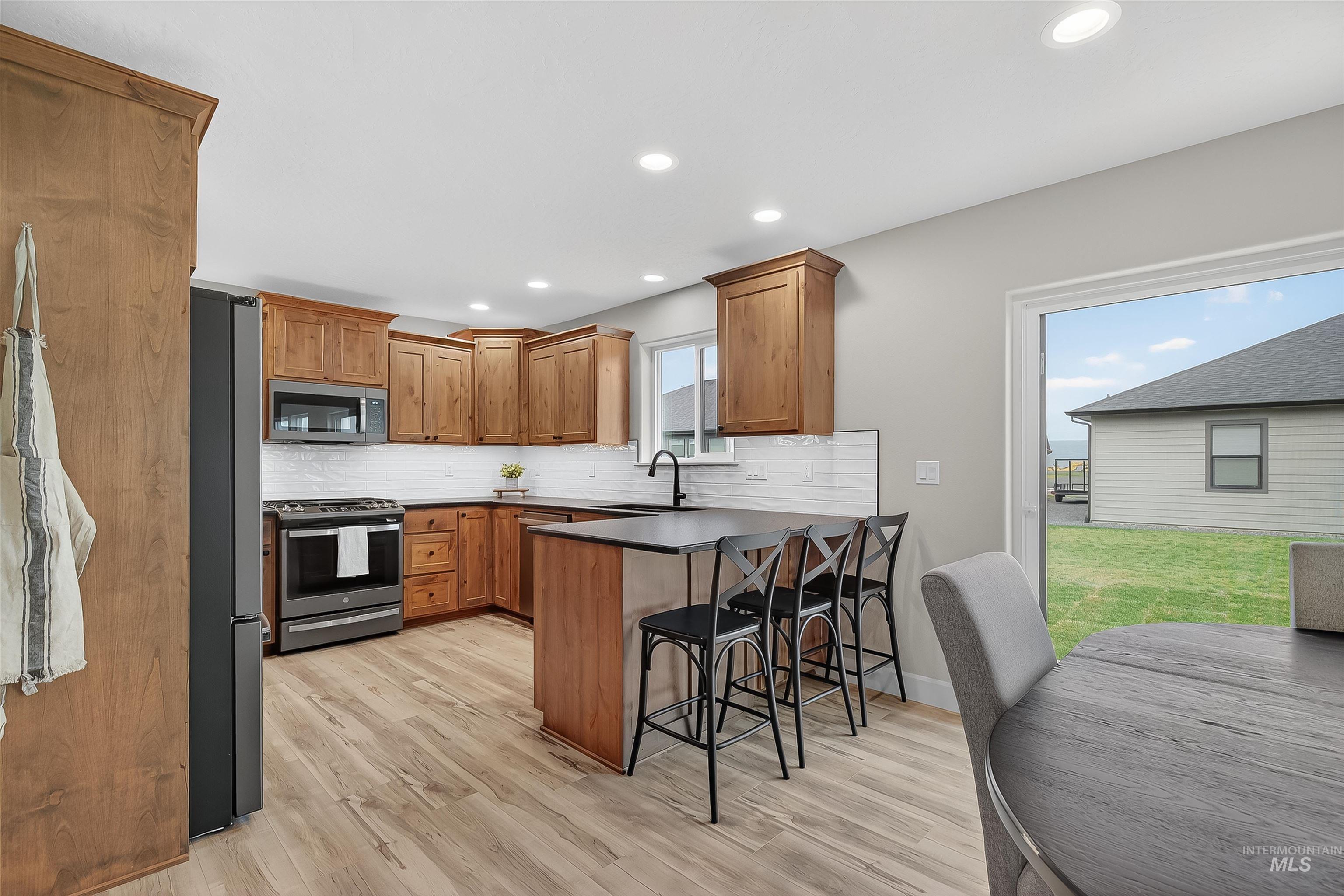 1725 Pathway Court Lewiston, ID 83501 - Photo 9 of 37 Kitchen featuring brown cabinets, appliances with stainless steel finishes, a breakfast bar area, a peninsula, and recessed lighting
