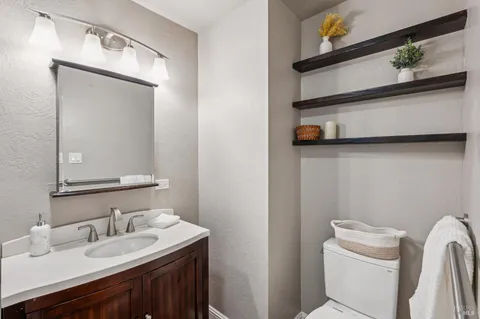 a bathroom with a granite countertop sink toilet and a mirror