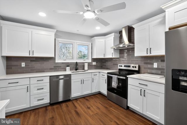 a kitchen with stainless steel appliances granite countertop a refrigerator a stove top oven a sink dishwasher and a refrigerator with wooden floor
