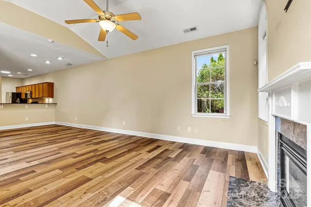 an empty room with wooden floor ceiling fan and windows