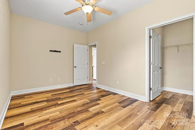 a view of a room with wooden floor and a ceiling fan